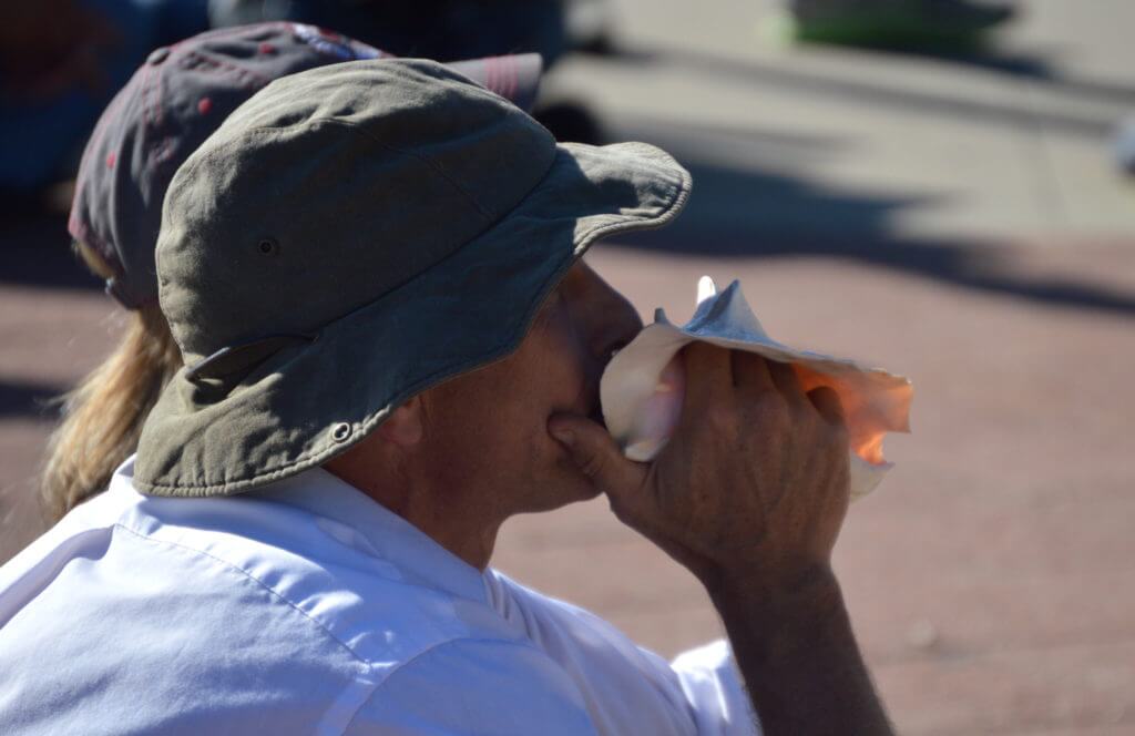 A man blows a conch for every applause line